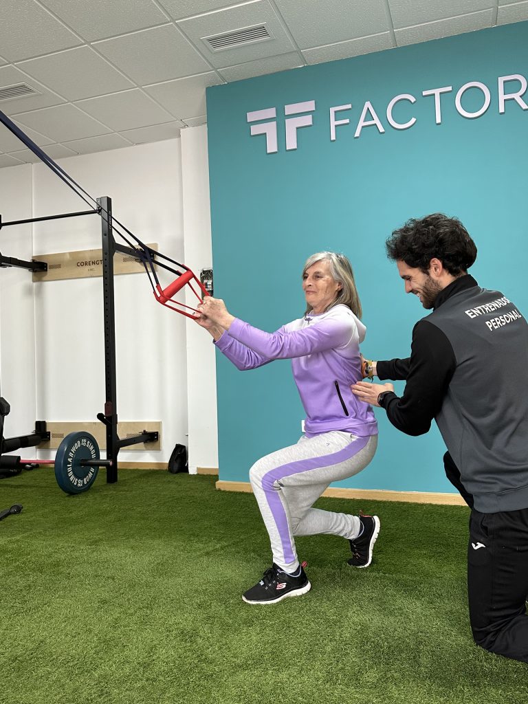 Se ve a una mujer de la tercera edad realizando un ejercicio controlado por su entrenador