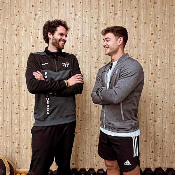 2 entrenadores mirándose de forma cómplice y sonriendo