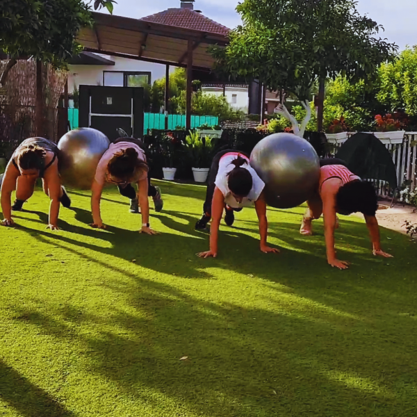 Se ve a 4 personas compartiendo un entrenamiento, haciendo conjuntamente un ejercicio